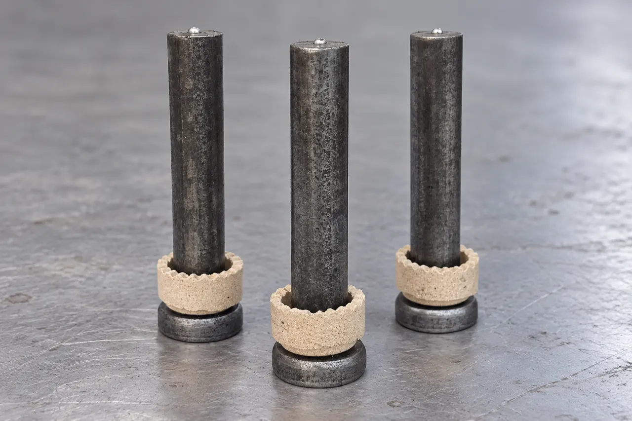 Cylindrical-head steel shear-stud samples beside separate ceramic ferrules